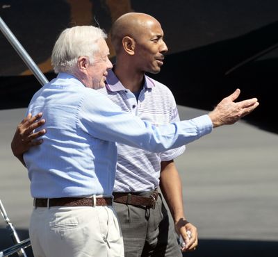 Aijalon Gomes is directed to his family by former President Jimmy Carter in Boston on Friday.  (Associated Press)