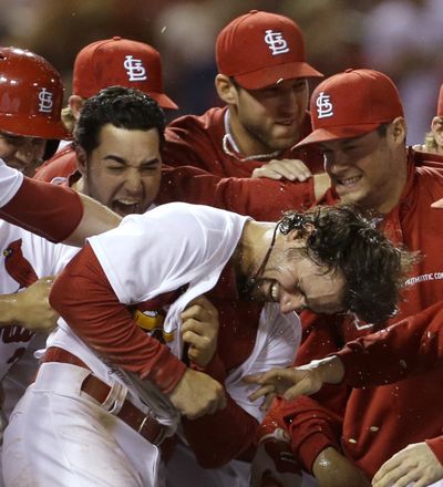 St. Louis Cardinals' Pete Kozma, center, is mobbed by teammates after scoring the game-winning run on a passed ball during the 10th inning of Friday night's game, a 2-1 victory for the Cardinals over the Mariners.
  (Jeff Roberson / Associated Press)