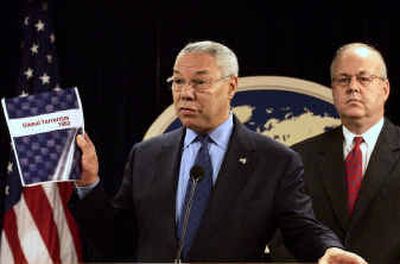 Secretary of State Colin Powell holds up a copy of the revised State Department terrorist report Tuesday in Washington. Behind him is J. Cofer Black, State Department coordinator for counterterrorism. 
 (Associated Press / The Spokesman-Review)