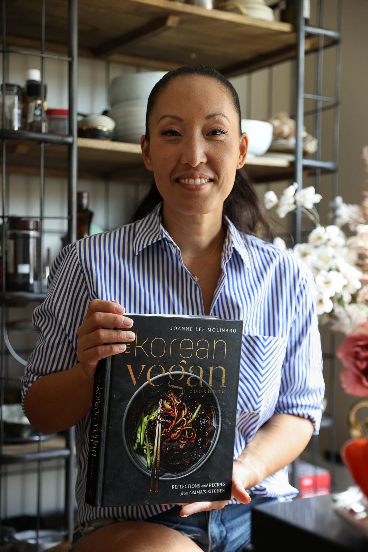 Joanne Lee Molinaro – with her book, “The Korean Vegan,” poses at home in Agoura Hills, Calif., on Sept. 11. Molinaro wanted her book to look just like her TikTok account, so she photographed the recipes herself and had her followers vote on the cover.  (JENI AFUSO/New York Times)