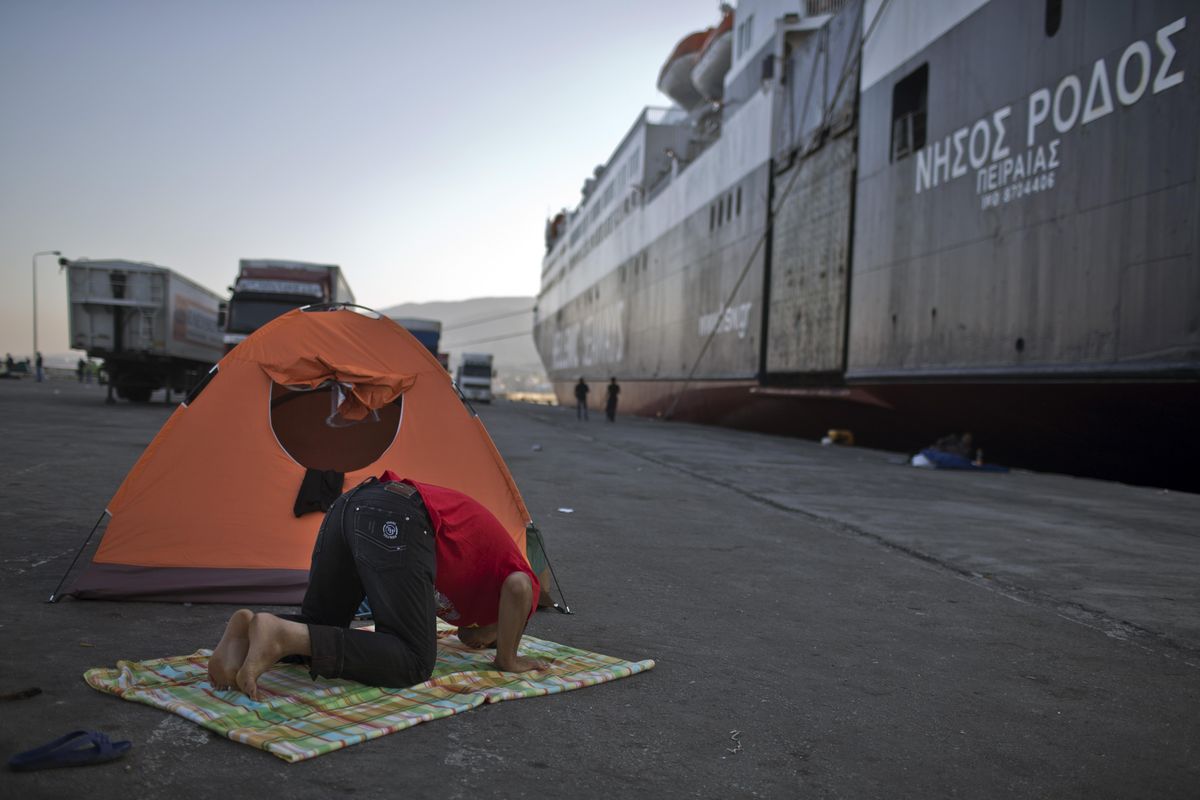 A man prays Thursday next to a ferry boat in the port of Mytilene, on the island of Lesbos, Greece. Greek ferries, which were on strike and have trapped thousands of refugees on eastern Aegean islands, will start operating again on Friday. (Marko Drobnjakovic / Associated Press)