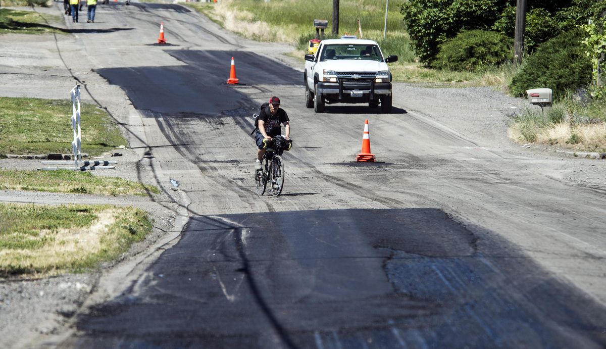 A cyclist and a city crew truck head south Thursday on Freya Street at Crown Avenue past the skin patches, June 22, 2107. (Dan Pelle / The Spokesman-Review)
