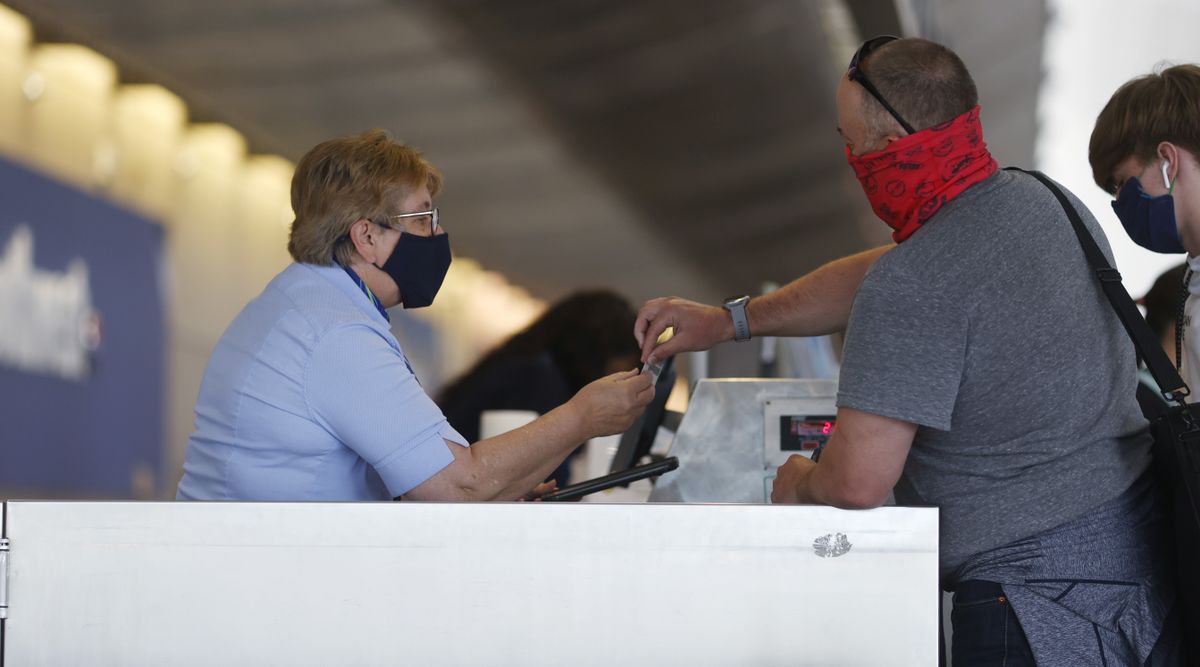 A traveler checks in with an agent at the counter for Alaska Airlines in the main terminal of Denver International Airport on Monday, June 22, 2020, in Denver during the coronavirus pandemic.  (David Zalubowski/Associated Press)
