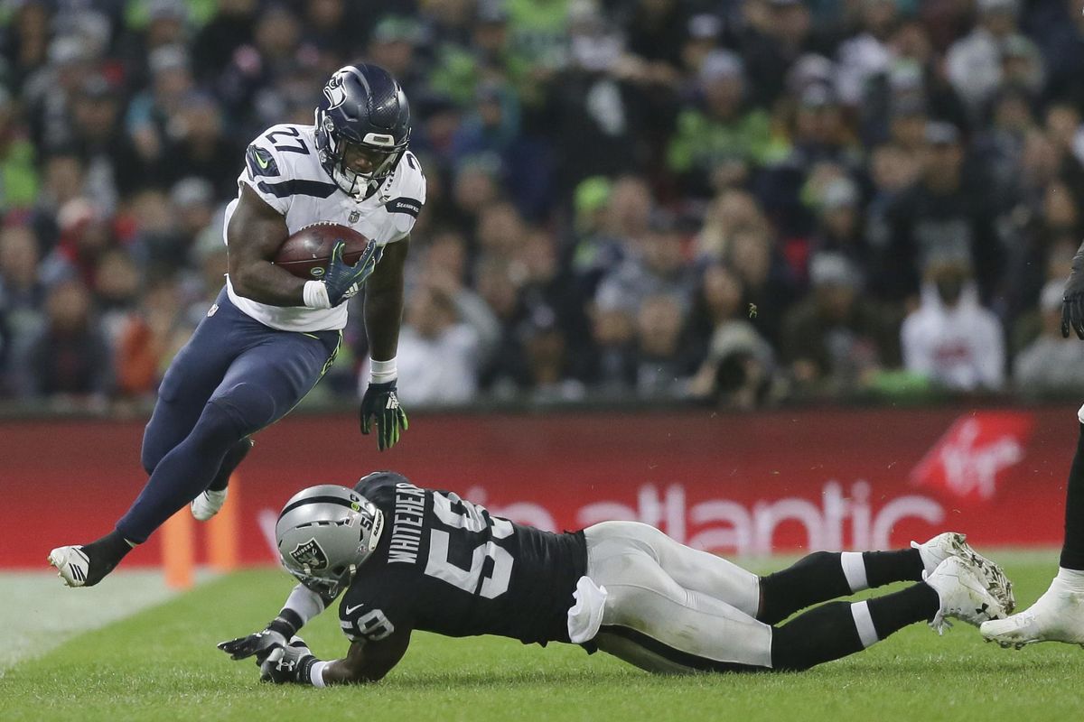 Seattle Seahawks running back Mike Davis (27), left, escapes the clutches of Oakland Raiders linebacker Tahir Whitehead (59) during the first half of an NFL football game at Wembley stadium in London, Sunday, Oct. 14, 2018. (Tim Ireland / Associated Press)