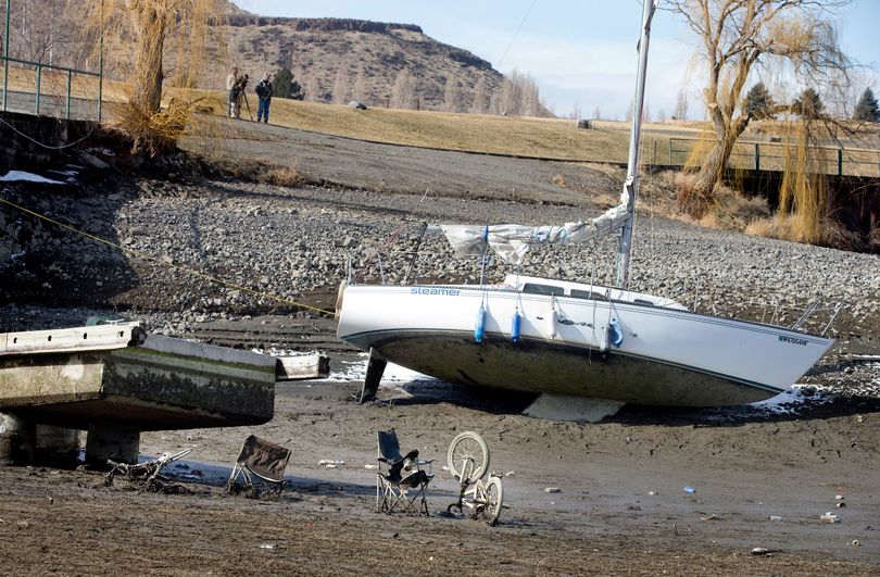 A sailboat owned by Bryan Stockdale, of Vantage, Wash., is left in the mud at the Vantage Riverstone Resort dock on Monday as up to 20 feet of water was let out of the Columbia River reservoir behind Wanapum Dam after a spillway pillar was discovered to be cracked at the dam last week. Garbage is seen that had been left in the water at the end of the dock. (Associated Press)