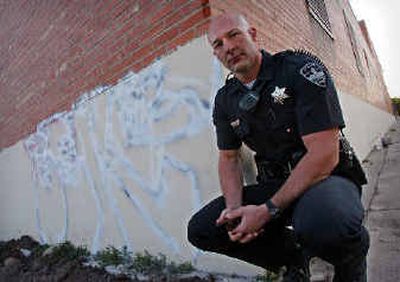 
 Boise Police Officer Brek Orton kneels beside covered up graffiti at a downtown warehouse in Boise on Friday morning. Orton has seen a steady rise in graffiti on buildings and other property around Boise in the last few years. 
 (Associated Press / The Spokesman-Review)