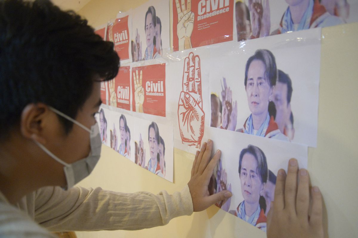 An anti-coup protester looks at the images of ousted Myanmar leader Aung San Suu Kyi during a protest against the military coup in Yangon, Myanmar, on Monday, April 26, 2021. Southeast Asian leaders have demanded an immediate end to killings and the release of political detainees in Myanmar during an emergency summit in Jakarta with its top general and coup leader.  (STR)