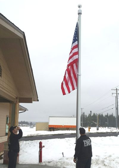 Firefighter Matt Church salutes as Engineer Dave Tysdal raises the flag to open Fire Station 4. (Coeur d'Alene Fire Department photo)