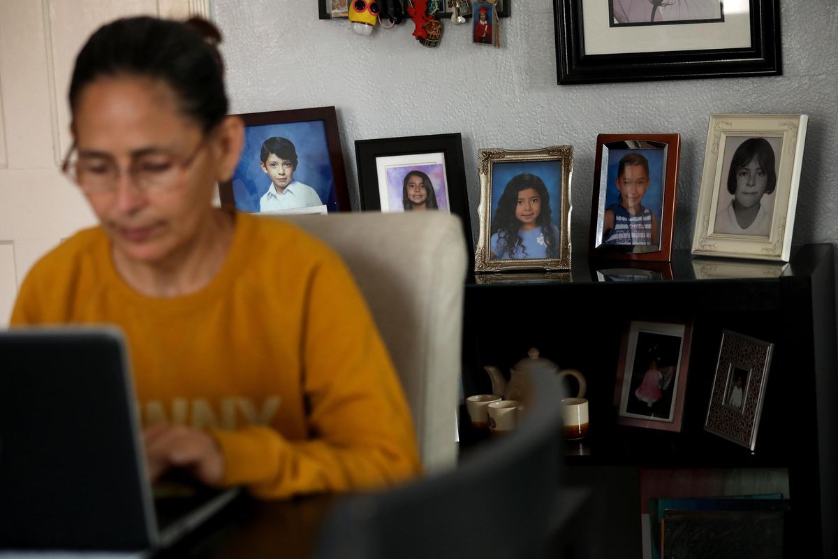 Claudia Alleman works on her computer, against a backdrop of photos of her family, in the living room of her family home in South Gate, California, on April 18, 2024. The Alleman family will be impacted when the federal internet subsidy program Affordable Connectivity Program will run out of funds next week. Thousands will be impacted in Los Angeles County when the program runs out of funds.   (Genaro Molina/Los Angeles Times/TNS)