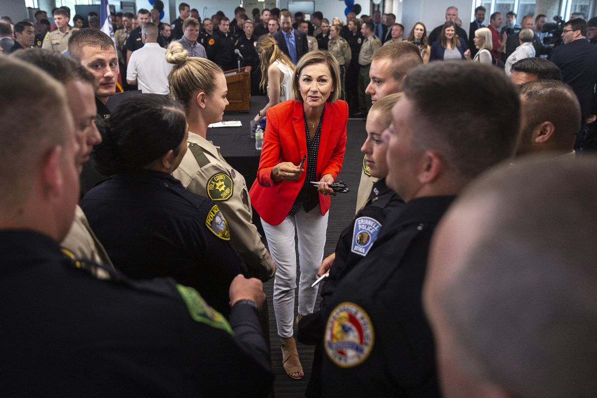 In this June 17, 2021 photo, Iowa Gov. Kim Reynolds hands out pens to law enforcement officers after signing the Back the Blue bill, at the Iowa Law Enforcement Academy, in Johnston. Some Republican-controlled states have responded to persistent calls for police reform by moving in the other direction. Reynolds signed a bill to expand qualified immunity for police officers and enhance penalties for protesters, including elevating rioting to a felony.  (Kelsey Kremer)