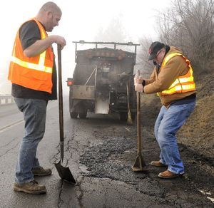 In this Jan. 28, 2011, SR file photo, columnit Doug Clark tamps down cold mix into a pothole on Cedar Road, repaired by City of Spokane Street Department's Justin Perry (left).