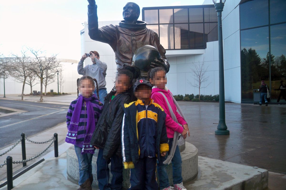 The faces of the children were digitally altered by the FBI to protect their identity in this photo taken Jan. 17, 2011, which shows Kevin Harpham in the background, photographing a family, along with the marchers assembled behind them. The bronze statue in the image commemorates the life of Lt. Col. Michael P. Anderson, who considered Spokane his hometown.