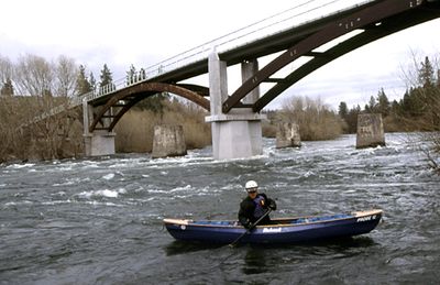 A kayaker paddles on Spokane River  near High Bridge Park. The Sandifur Memorial Bridge stands  in the background. (FILE photo / The Spokesman-Review)