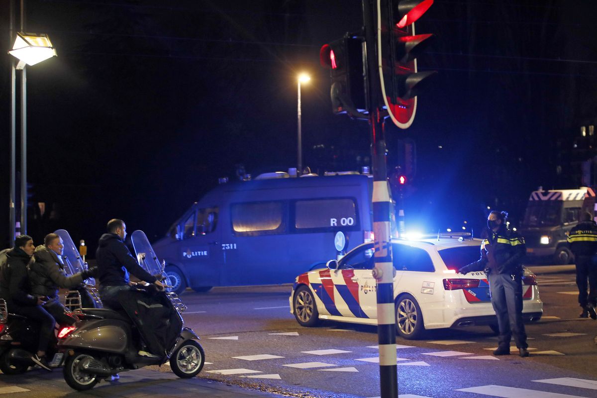 A police officers speaks to youths on scooters at a road block during a nation-wide curfew in Amsterdam, Netherlands, Tuesday, Jan. 26, 2021. The Netherlands entered its toughest phase of anti-coronavirus restrictions to date, imposing a nationwide night-time curfew from 9 p.m. until 4:30 a.m. which started Saturday Jan. 23, 2021, in a bid to control the COVID-19 infection rate.  (Peter Dejong)