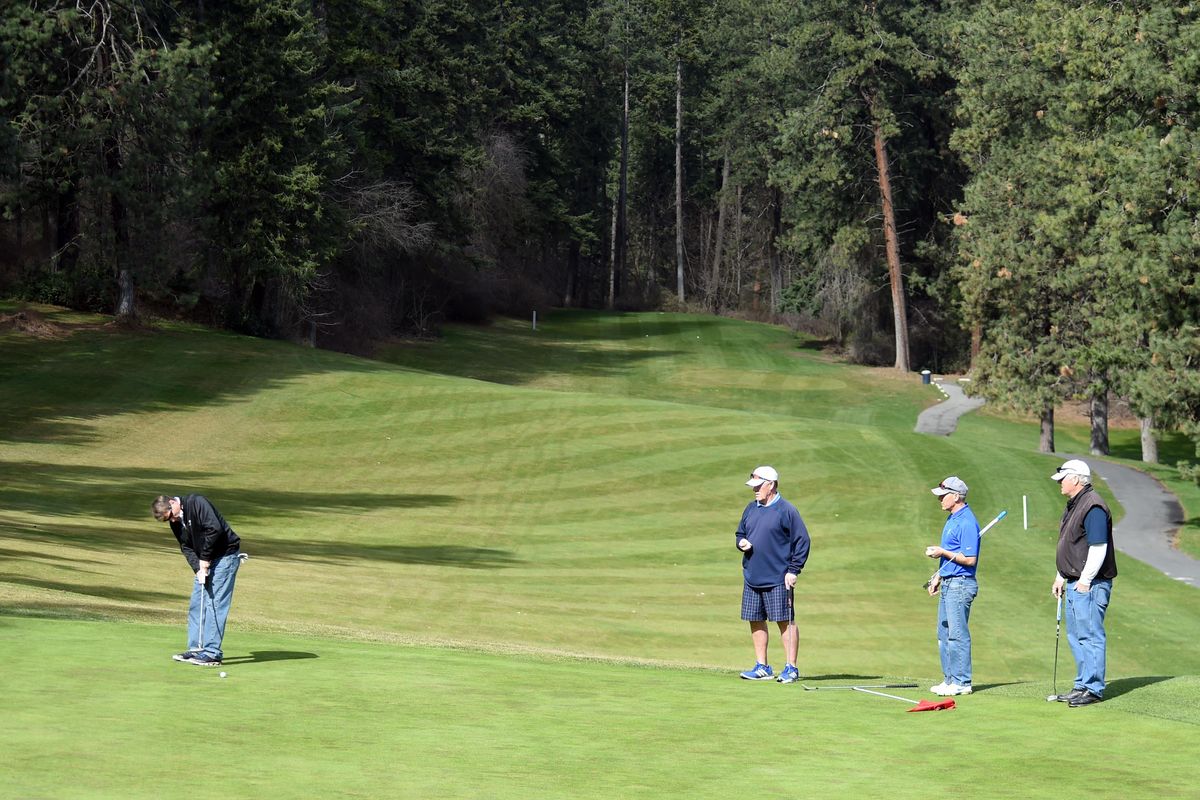 Dan Fay, left, putts in while members of his regular foursome, Marv Richardson, Ryan Sandvig and Randy Allen, watch at Indian Canyon Golf Course Monday, Mar. 21, 2016, the first day of operations for the course. The course' pro shop and clubhouse are currently being remodeled and should be completed by late April under the direction of the new course pro, Doug Phares, who was hired in January. (Jesse Tinsley / The Spokesman-Review)