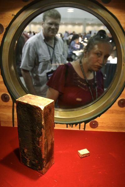  Coin collector Darlene Corio, of Rochester, N.Y., right, peers Tuesday through a  window at a gold ingot weighing more than 662 ounces at the World’s Fair of Money in Boston.  (Associated Press)