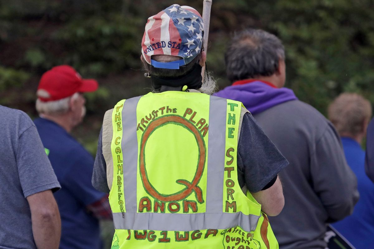 FILE - In this May 14, 2020, file photo, a person wears a vest supporting QAnon at a protest rally in Olympia, Wash., against Gov. Jay Inslee and Washington state stay-at-home orders made in efforts to prevent the spread of the coronavirus. President Joe Biden