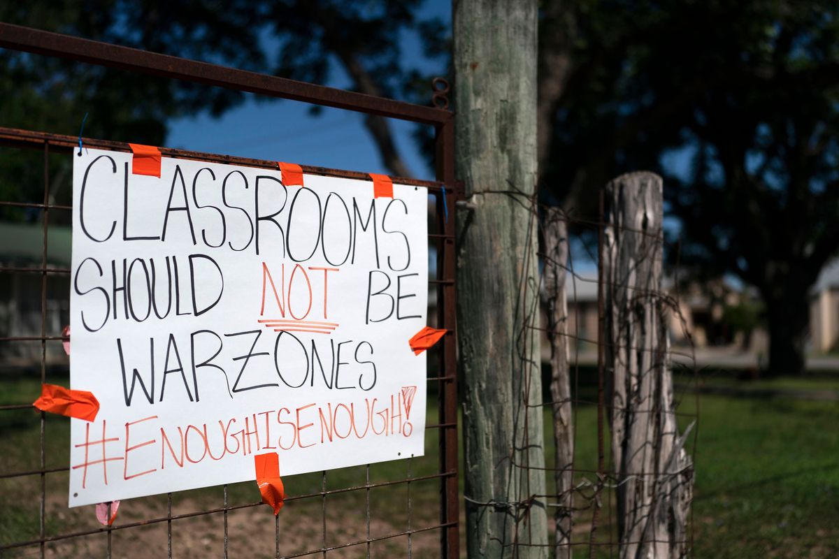 A sign asking for change hangs on a fence near Robb Elementary School in Uvalde, Texas, on Friday.  (Jae C. Hong)