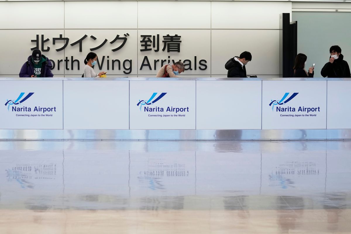 FILE - Passengers wait in line before moving onto their temporary housing for quarantine as they come out of an arrival gate for international flights at the Narita International Airport in Narita, east of Tokyo, on Dec. 2, 2021. Japan will ease its much criticized coronavirus border controls, but the new policy only allows 5,000 new entrants per day, up from 3,500, including Japanese nationals, beginning March 1.  (Hiro Komae)