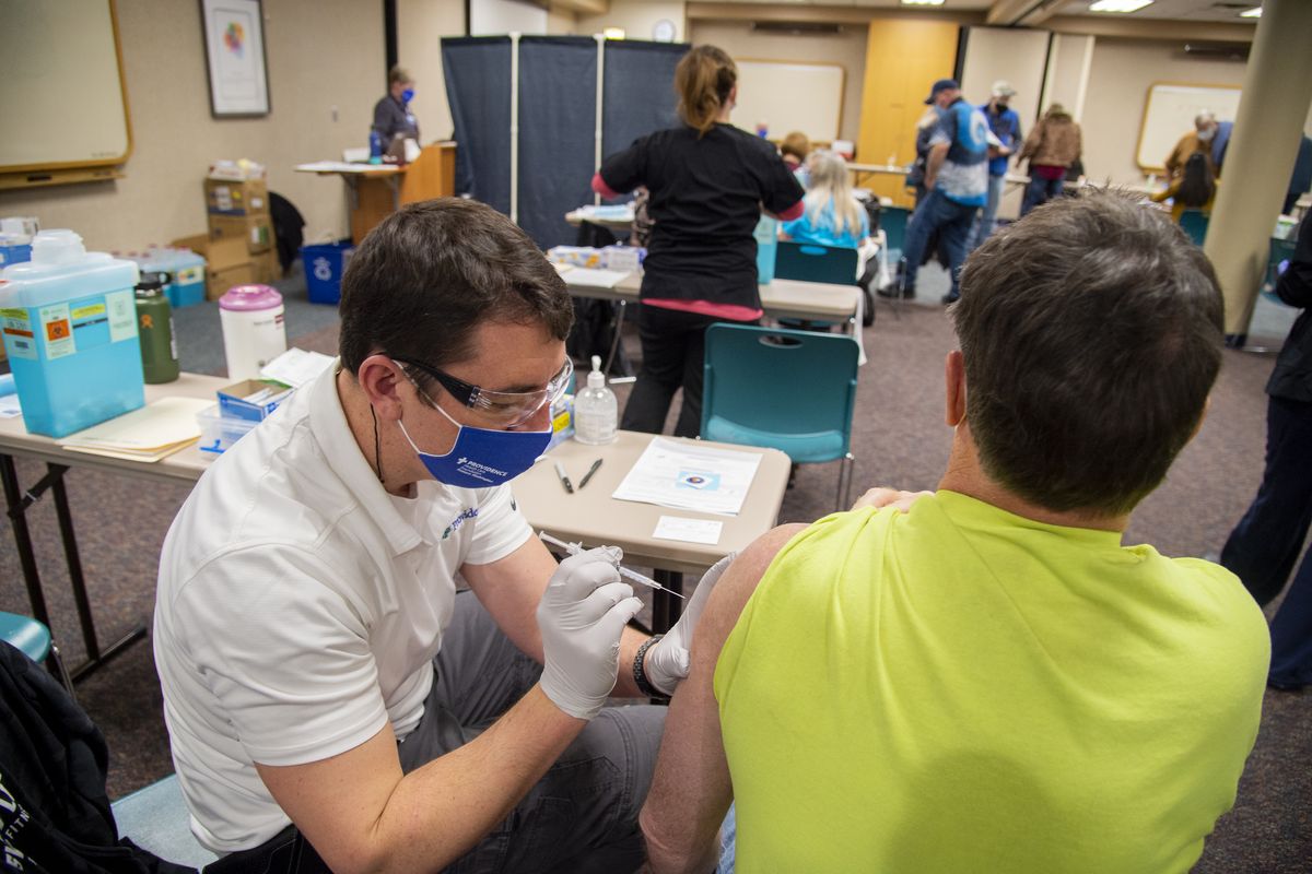 Nurse Brian Baker, left, administer’s the first dose of the Moderna COVID-19 vaccine to Michael Toth, right, Friday, Jan. 22, 2021, at a pop-up clinic at Holy Family Hospital in north Spokane. Providence, which runs Holy Family, has not yet instituted a vaccine mandate for hospital employees. MultiCare has.  (Jesse Tinsley/The Spokesman-Review)