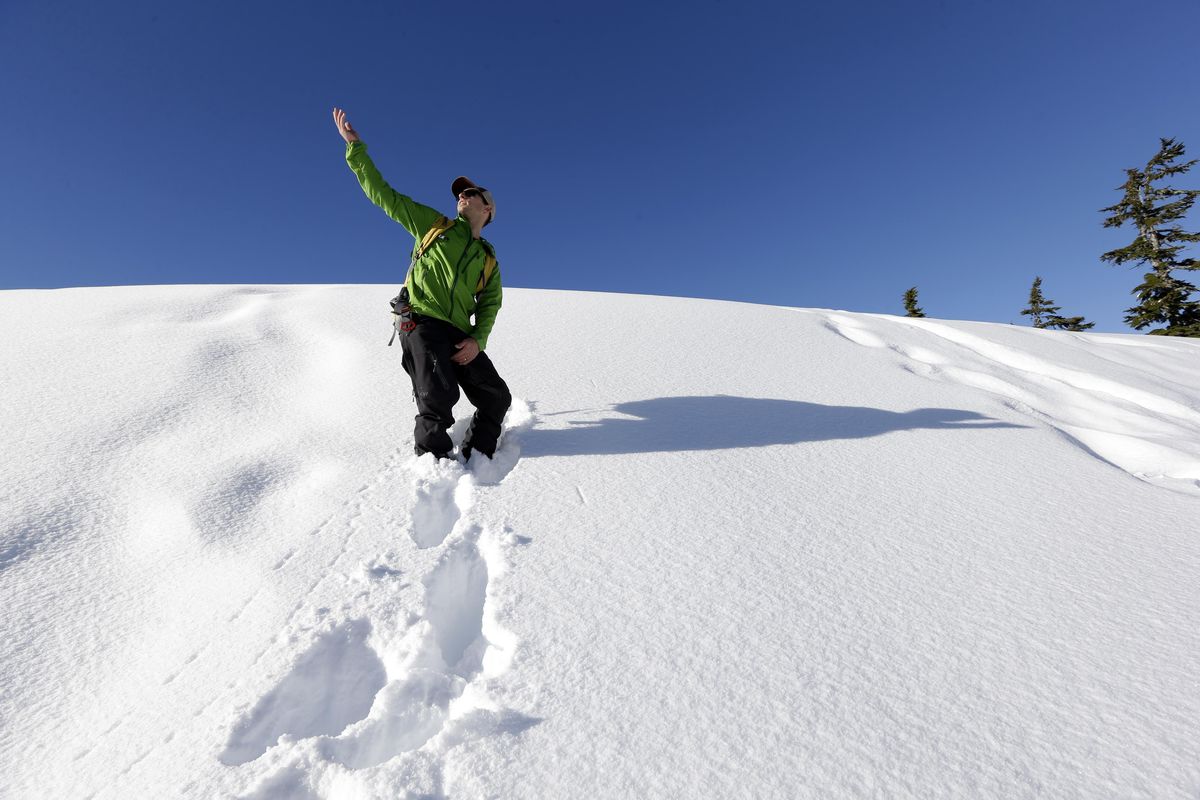 Eric Gullickson, an instructor with the Northwest Avalanche Center, points toward the sky as he explains how a slope heated by the sun can affect the possibility of an avalanche as he leads teenagers on an avalanche awareness field trip at Mount Baker, Washington. As more young adults head out of bounds to ski, snowboard or hike in the winter, experts are targeting their message about avalanche safety and knowledge to an even younger audience. (Elaine Thompson / Associated Press)