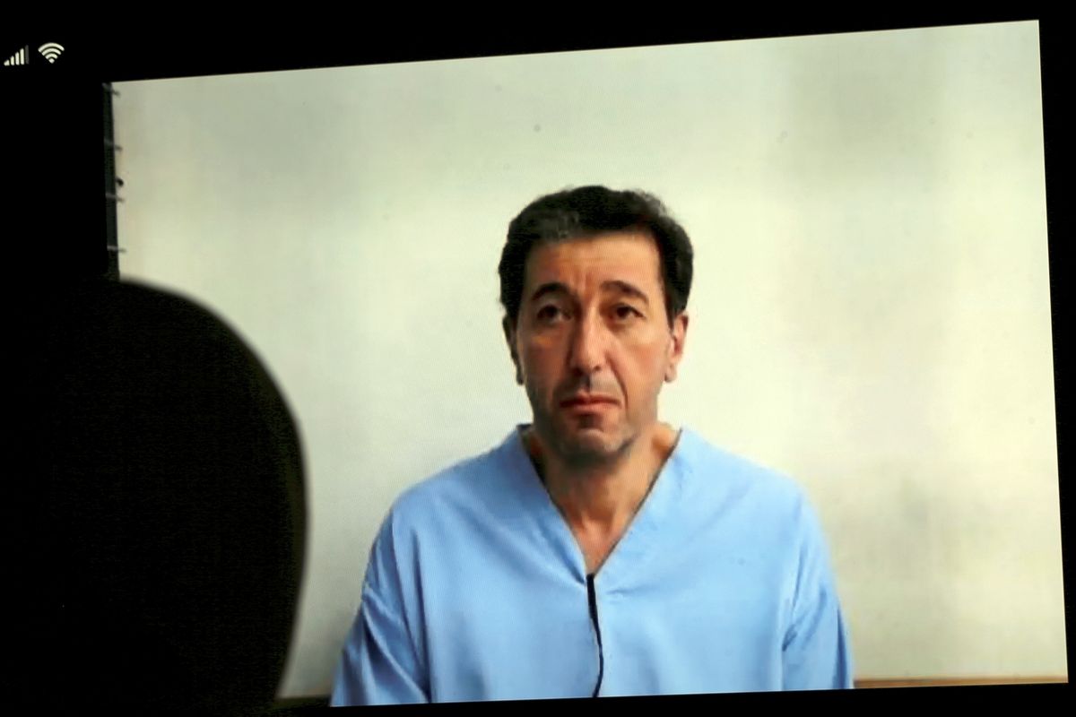 Bassem Awadallah, one of two former officials accused of helping Jordanian Prince Hamzah try to overthrow his half-brother King Abdullah II, appears on a mobile phone screen as he attends a verdict hearing at a state security court, in Amman, Jordan, Monday, July 12, 2021. The court sentenced the two to 15 years in prison. Awadallah, who has U.S. citizenship and once served as a top aide to King Abdullah II, and Sharif Hassan bin Zaid, a member of the royal family, were found guilty of sedition and incitement charges. (Raad Adayleh)