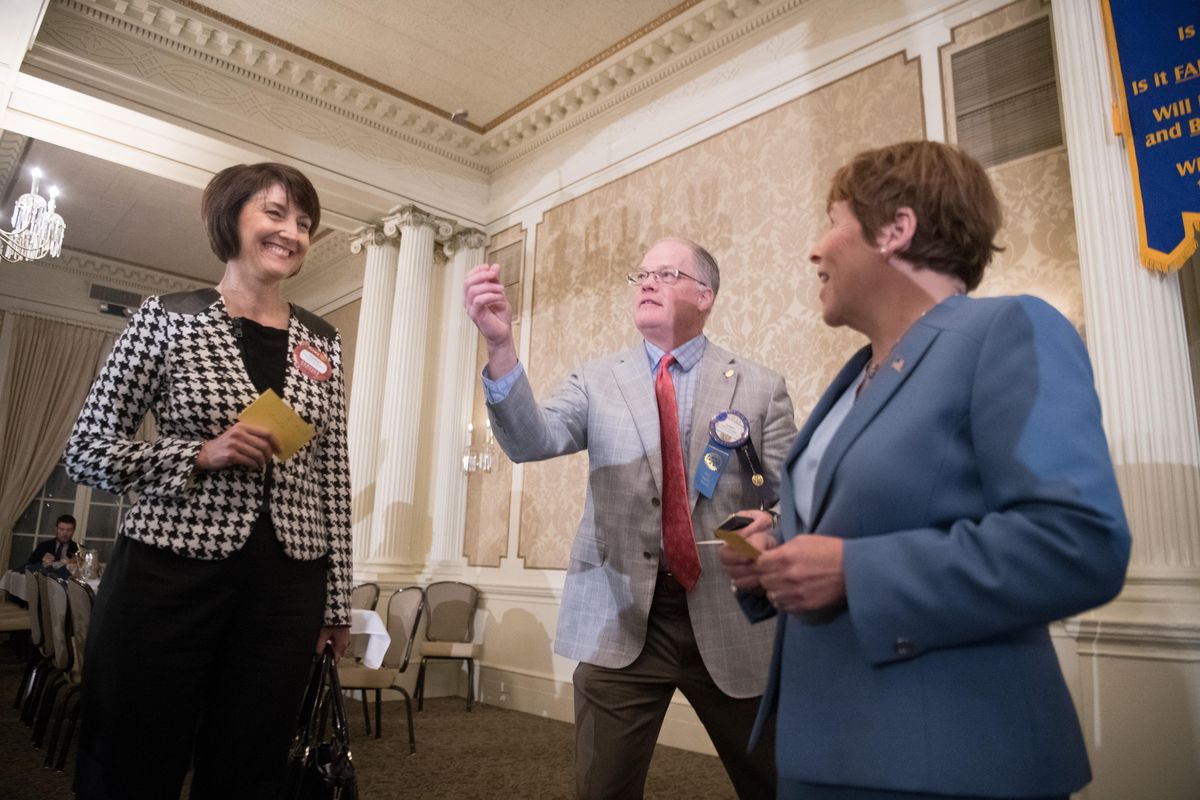 Cathy McMorris Rodgers, left, and Lisa Brown react as John Pilcher flips a  coin before a debate hosted by Spokane Rotary Club 21 on Thursday, Oct. 18, 2018, at the Spokane Club in Spokane, Wash. McMorris Rodgers won the coin toss. (Tyler Tjomsland / The Spokesman-Review)