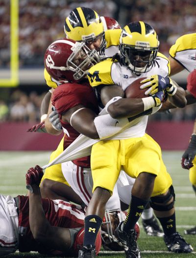 Michigan running back Vincent Smith is wrapped up by Alabama’s Ed Stinson. (Associated Press)