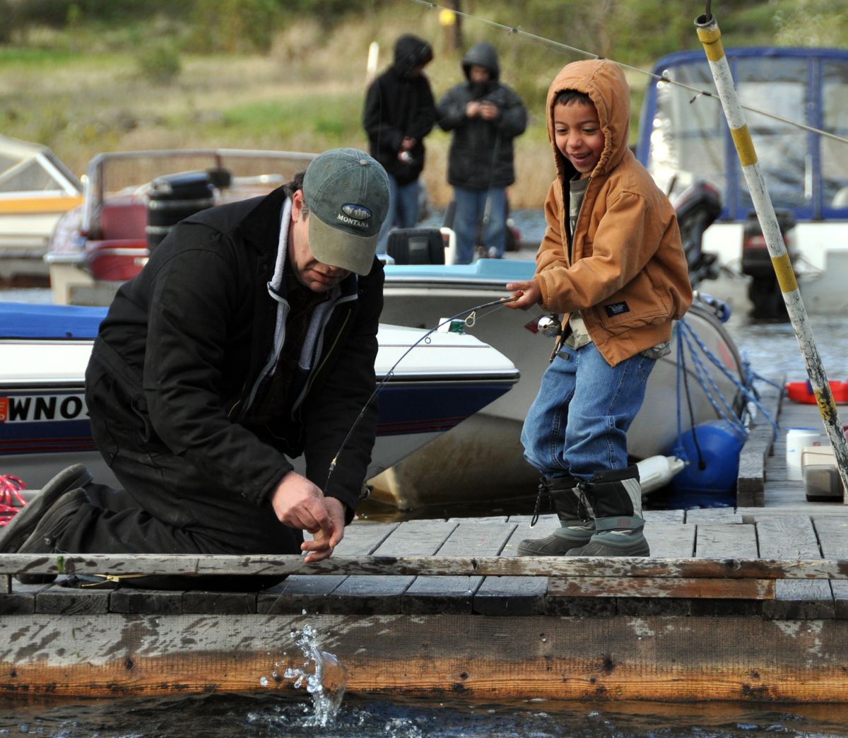 Ted Urban, of Spokane, helps nephew Christopher Salinas land his first fish on the docks at Fishtrap Lake Resort on Saturday. (Rich Landers)