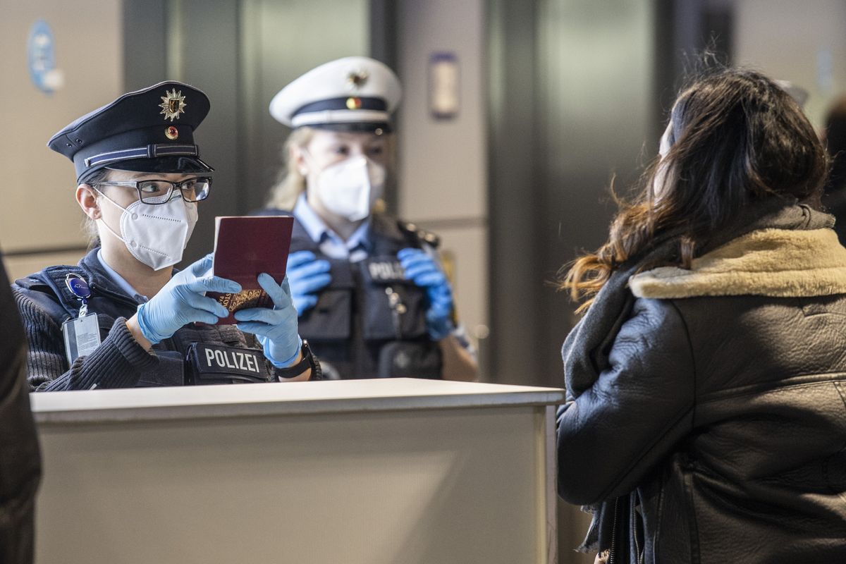 In this Sunday, Jan. 24, 2021 photo, officers of the German Federal Police check passengers arriving by plane from Prague at the Frankfurt Airport in Frankfurt, Germany. The European Union