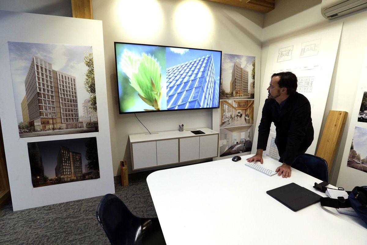 In this Nov. 15, 2016, file photo, Lever Architecture founder Thomas Robinson looks over artist renderings in Portland, Ore., of a 12-story all-wood building that his firm is working on to be built in Portland’s trendy Pearl District. City officials in Portland have approved a construction permit for the first all-wood high-rise building in the nation. Developers announcing the approval Tuesday, June 6, 2017, say it’s a milestone for wood technology. (Don Ryan / Associated Press)