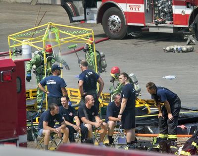 Spokane firefighters gather in a decontamination area outside the Pacific Steel and Recycling building Wednesday after responding to a chemical leak. (Dan Pelle / Coeur d'Alene Press)