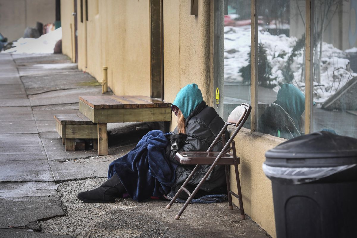 A homeless person cuddles with a dog outside the Cannon Street shelter, Tuesday, March 12, 2019, in Spokane. The Spokane City Council once again balked Monday on a proposal to ban devices that emit high-pitched noises to disperse young and homeless people from areas near downtown businesses. (Dan Pelle / The Spokesman-Review)