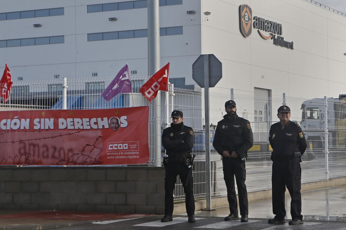 Police guard the entrance of the main Amazon Logistics Center where goods are stored for distribution, on the outskirts of Madrid, Spain, on Friday, Nov. 22, 2018. Amazon workers are staging a 2-day strike coinciding with Black Friday over a labour dispute. Banner reads ‘Explotation without rights’. (Paul White / AP)