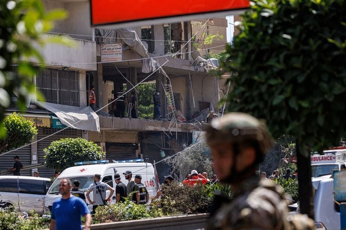 A Lebanese army officer keeps watch Sunday as police officers and emergency personnel work at the site of an Israeli strike on the southern suburbs of Beirut.  (Reuters )