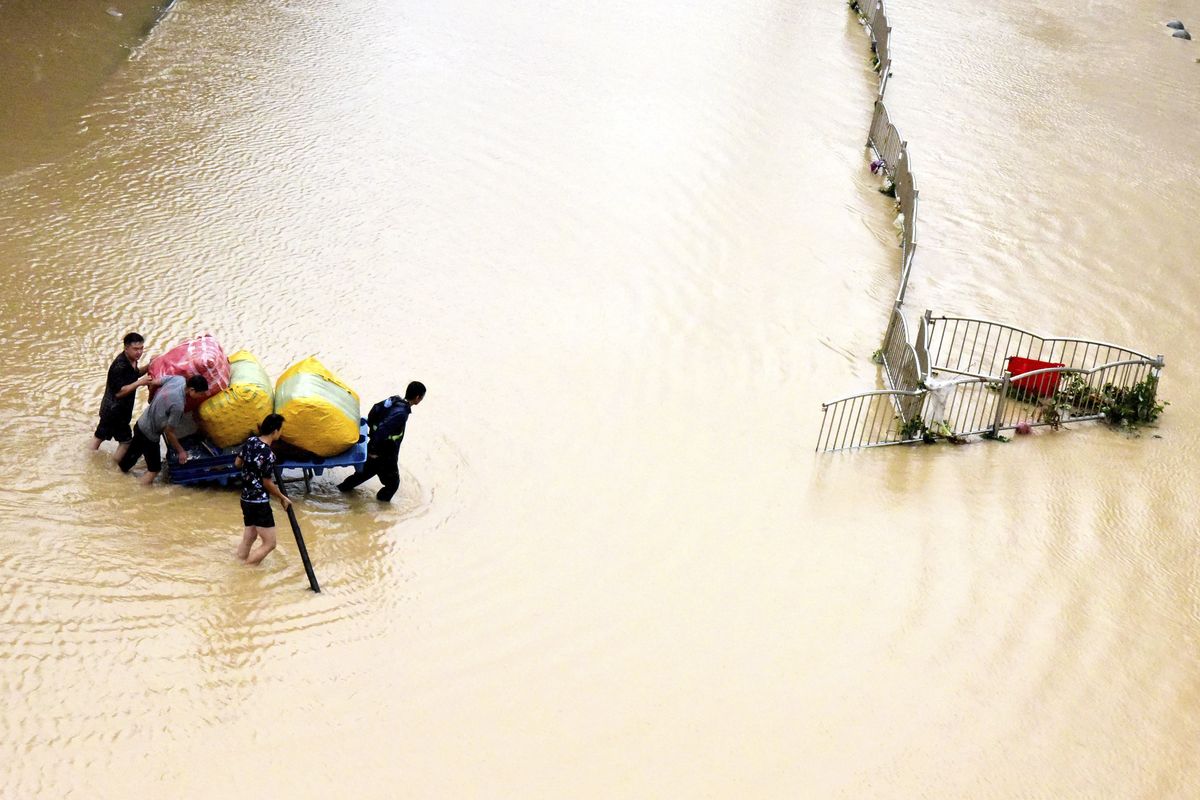 In this photo released by Xinhua News Agency, residents move their belongings across a flooded street in Zhengzhou in central China
