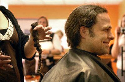 
Jesse Hansen is all smiles as The Man Shop manager and stylist Kim Fields holds up his ponytail moments after she cut it off. Hansen had his hair cut to honor his late brother-in-law. 
 (Jed Conklin / The Spokesman-Review)