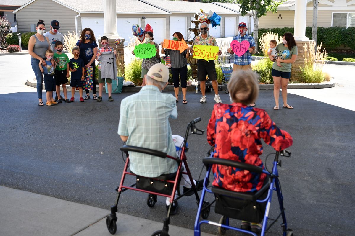 Tony Marcelli and his wife Marie wave to family members during a socially distanced 100th birthday party outside his retirement home on Saturday, Aug. 15, 2020, at Evergreen Fountains in Spokane Valley, Wash.  (Tyler Tjomsland/THE SPOKESMAN-REVIEW)
