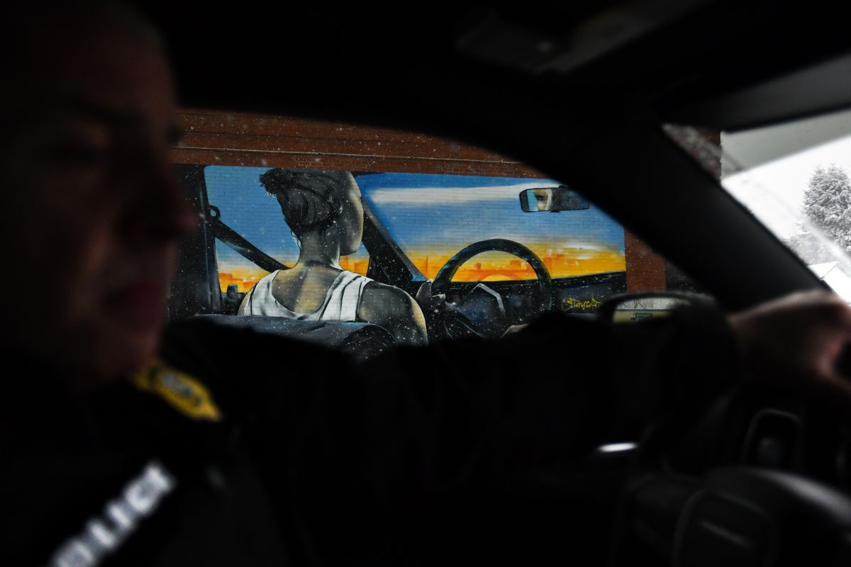 Sgt. Kurt Vigesaa is seen in silhouetted profile as he drives past a mural of a woman driving a car though Spokane while patrolling on Friday, Feb. 8, 2019, in Spokane. (Tyler Tjomsland / The Spokesman-Review)