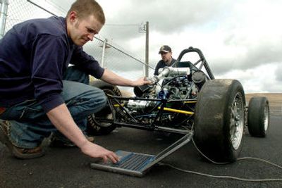 
Chuck Dean, left, and Josh Bingham with Vandal Racing fine-tune the fuel mixture. The low-slung, three-gear racer has a top speed of about 70 mph. 
 (The Spokesman-Review)