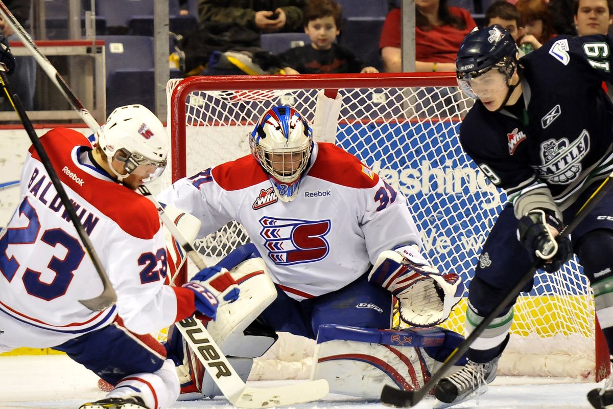 Spokane defender Corbin Baldwin and goalie Mac Engel try to beat Seattle’s Colin Jacobs to loose puck in front of Chiefs’ goal. (Jesse Tinsley)