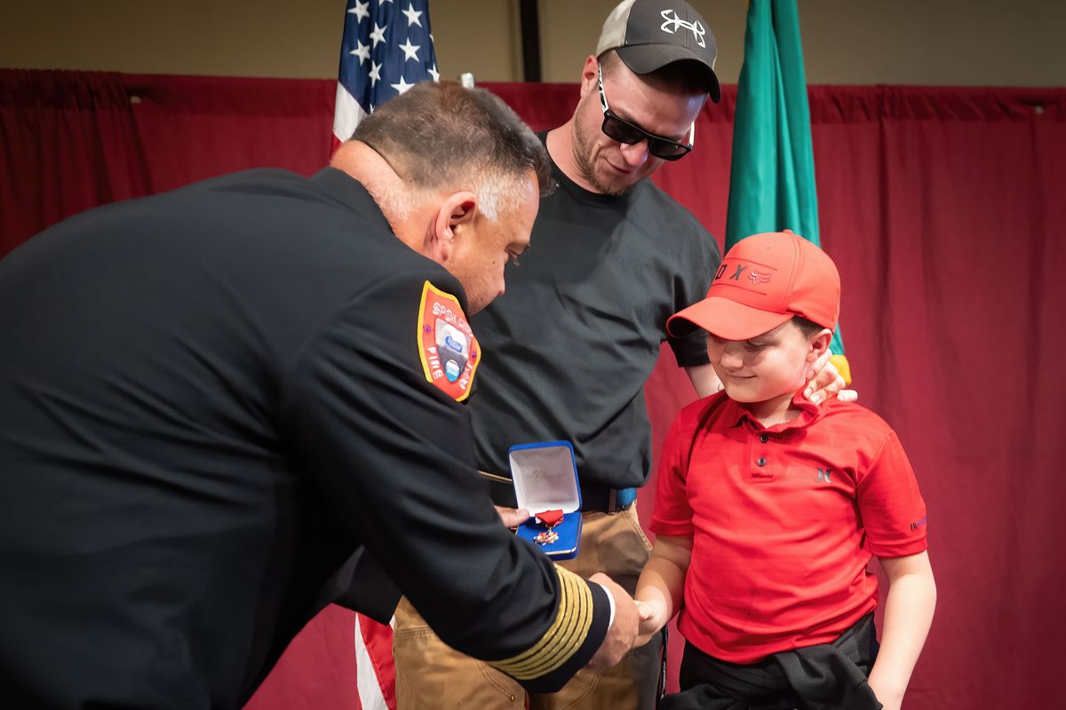 With his father Steve Braley by his side, Spokane Fire Chief Tom Williams presents Londyn Braley, age 7, with department’s Citizen Community Lifesaving Award on Thursday during the SFD awards ceremony.  (COLIN MULVANY /THE SPOKESMAN-REV)
