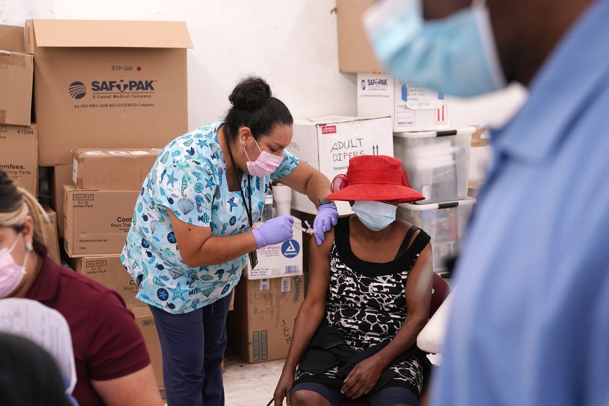 FILE - In this April 10, 2021, file photo, registered nurse Ashleigh Velasco, left, administers the Johnson & Johnson COVID-19 vaccine to Rosemene Lordeus, right, at a clinic held by Healthcare Network in Immokalee, Fla. With coronavirus shots now in the arms of nearly half of American adults, the parts of the U.S. that are excelling and those that are struggling with vaccinations are starting to look like the nation’s political map: deeply divided between red and blue states. (Lynne Sladky)