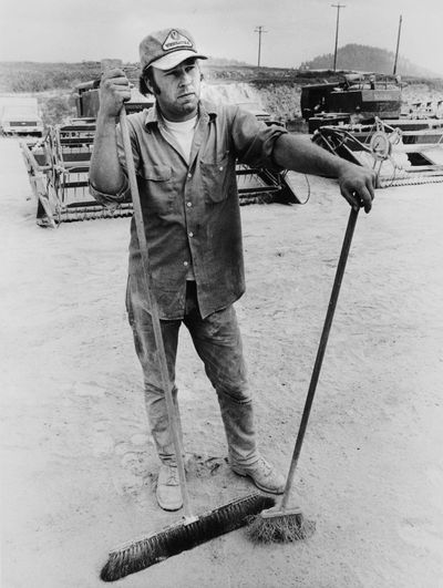 Phil Gage, an employee of Best Way Equipment in Palouse, Washington, takes a break from sweeping off ash-covered farm implements in this photo from June 10, 1980. (Phil Schofield / S-R)