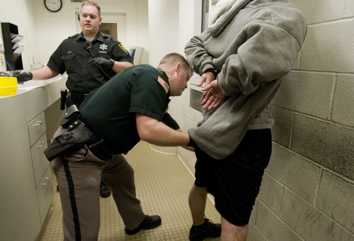 Deputy Jake Pietz searches a man Friday during booking procedures at the Spokane County Jail. The man was arrested on an outstanding warrant.  (Colin Mulvany / The Spokesman-Review)