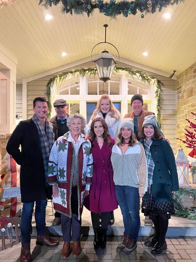 The cast of Hallmark’s “Haul Out the Holly” poses on set in Salt Lake City this summer. Pictured are (top row from left) Wes Brown, Walter Platz, Melissa Peterman and Stephen Tobolowsky, and (front row from left) Ellen Travolta, Lacey Chabert, Eliza Hayes Maher and Laura Wardle.  (Courtesy of Ellen Travolta)