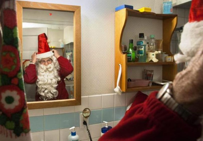 Bob Conrad adjusts his Santa Claus hat and beard in the bathroom mirror, Dec. 9, 2015, at his Spokane Valley home. Conrad played Santa at the Crescent Building in the 1990s. (Dan Pelle/SR)