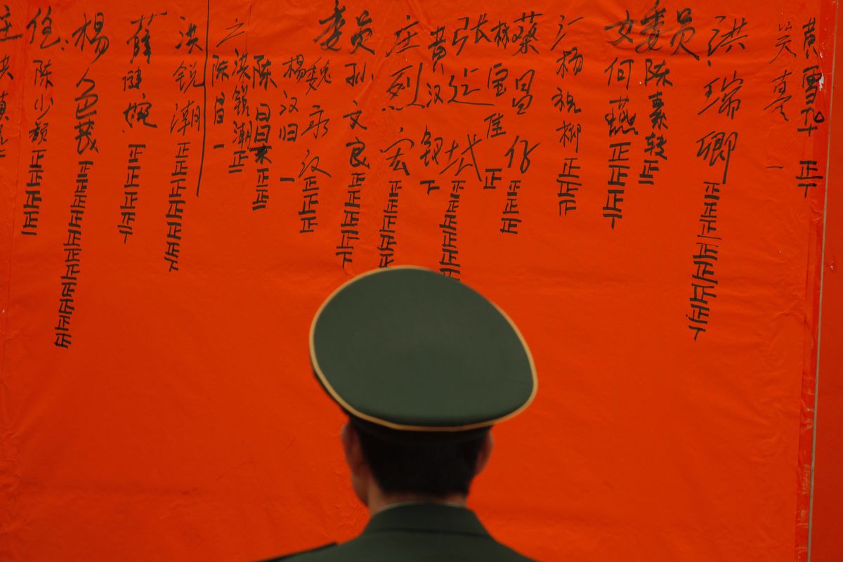 A Chinese police officer guards a board showing election results in Wukan village, China, on Saturday. (Associated Press)