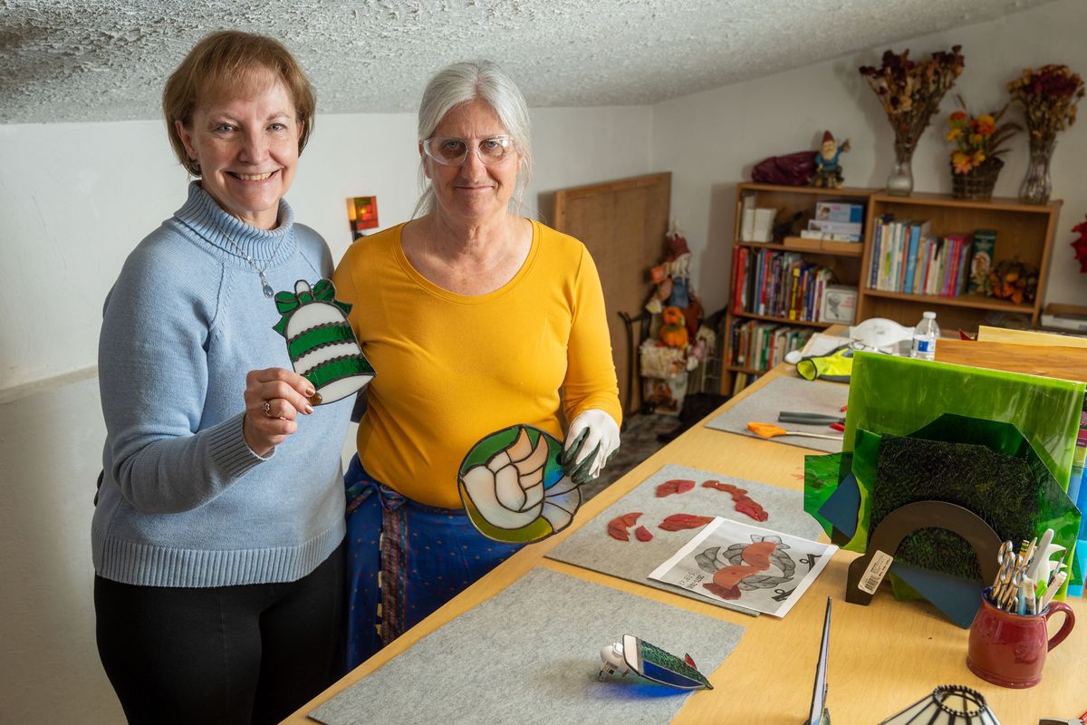 Nancy Vocature, on left, had hoped to share her love of stained glass in a group setting at her home studio, but the pandemic derailed that plan. Instead, she met with her friend Belinda Cron, on right, each week and taught her the craft. They produced five patio tables, numerous sun catchers and a large stained glass window.  (COLIN MULVANY/THE SPOKESMAN-REVI)
