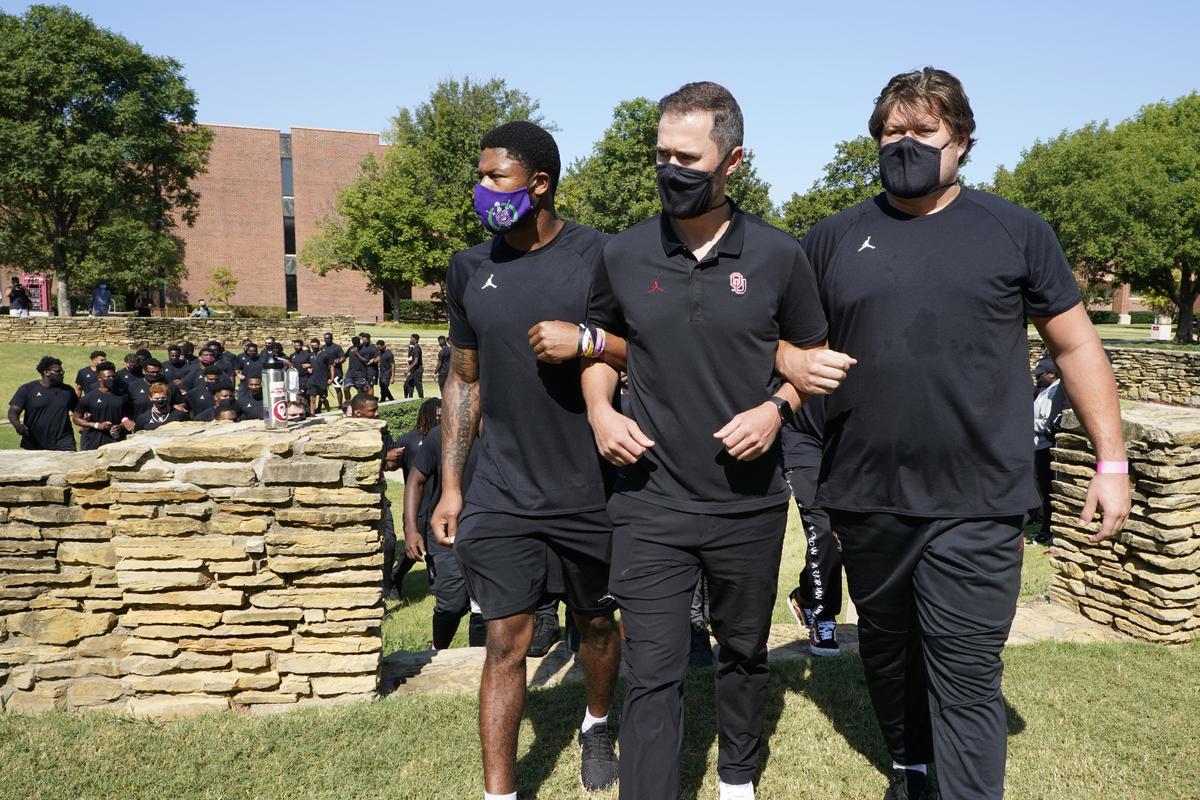 Chanse Sylvie, left, head coach Lincoln Riley, center, and Creed Humphrey, right, lead the Oklahoma football team from the Unity Garden after they held a 57-second moment of silence in honor of the 57-year anniversary of the March on Washington and Dr. Martin Luther King, Jr.